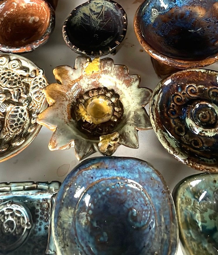 Collection of handbuilt ceramic incense holders with various glazes including blues, browns and earth tones